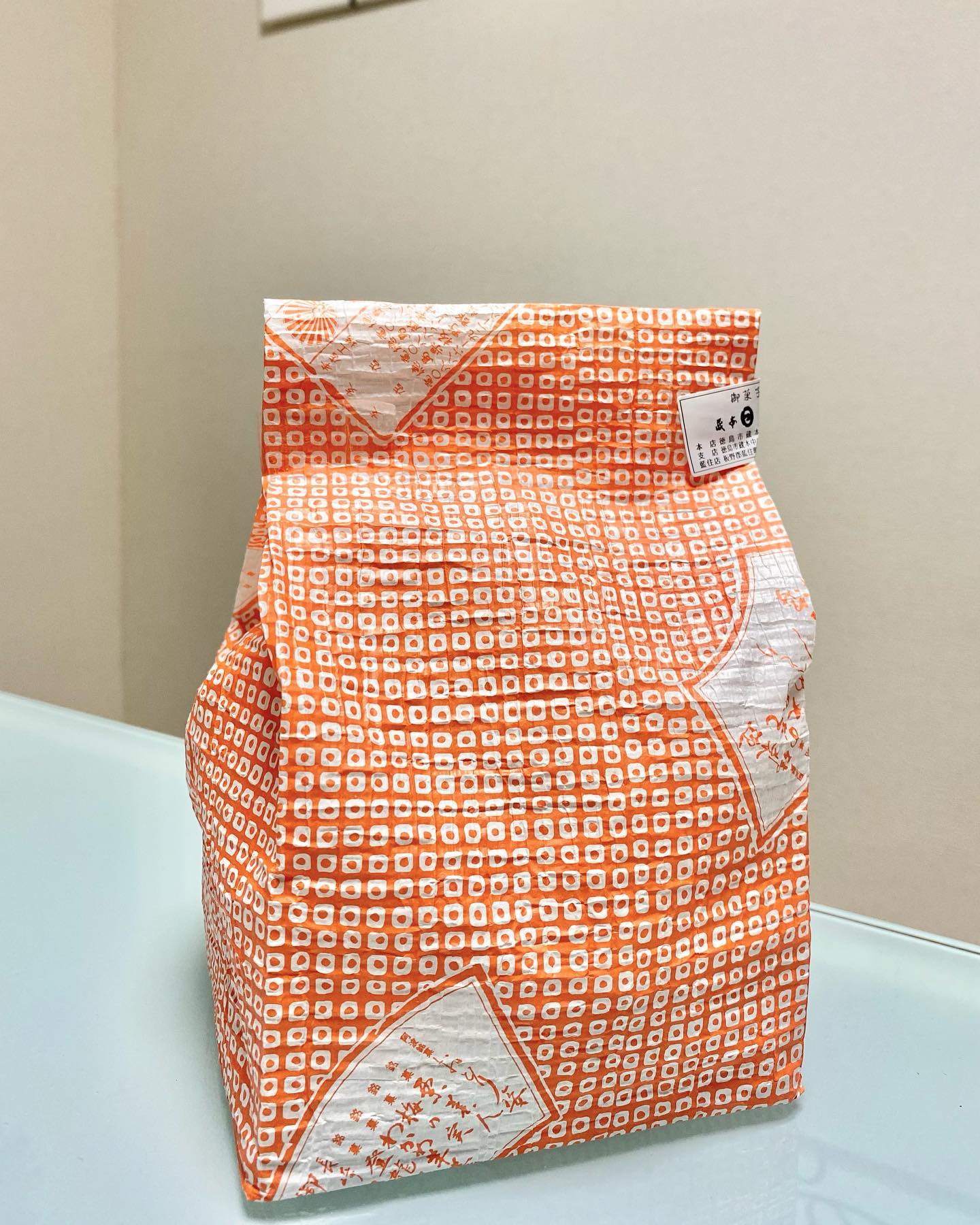 studio prismのホームページに掲げていることのひとつが、理想のイメージを叶えるのは色、形、質感のトータルコーディネートということです。それはファッション、インテリア、パッケージなど、あらゆることに当てはまります。今日それを自分の感覚を通じて実感した出来事がありました。今後のお仕事の下見で徳島に行って来たのですが、帰りに徳島の和菓子の老舗、『くらもと 日の出』さんに立ち寄りました。どら焼き、上生菓子などいくつかのお菓子を選ばせていただき、お店の方が「ありがとうございました」と差し出して下さった紙袋を受け取った時のことです。お店の方のお顔を見ていた私は無意識に受け取ったその紙の手触りにハッとして、思わず袋を見たのです。それは日の出を思わせるオレンジ色の総柄の鹿の子絞りのちりめん生地のように見えた、だけでなく、感じられたのです。よくあるツルツルとした包装紙のような紙ではなく、ふんわりと柔らかくシボシボとした手触りの和紙のような紙。お店の名前を思わせる色使い、日本の伝統と技術が感じられる柄、そしてそれを視覚だけでなく触覚でも紙袋で表現されているところに、『くらもと 日の出』さんの老舗和菓子屋さんとしての心意気や心遣いを感じ、素晴らしいな、と思いました。感動は日常の中にありますね。それをキャッチ出来るように、感覚を大切にしていたいです。#感動は日常の中にある #くらもと日の出 #上生菓子#どら焼き#徳島#徳島和菓子 #感覚 #感動#感覚を大切に#鹿の子絞り #色#形#質感#studioprism